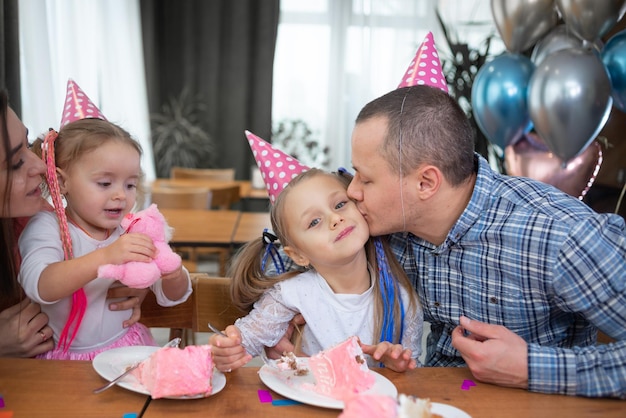 Uma família caucasiana está sentada em casa à mesa chapéus de festa são usados em suas cabeças Conceito de aniversário familiar