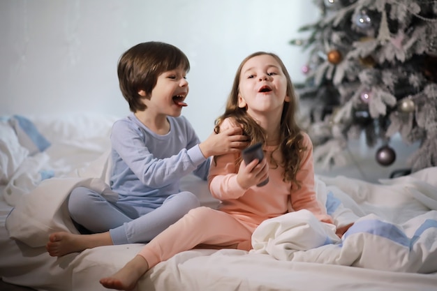 Uma família com crianças se divertindo na cama sob as cobertas durante as férias de Natal.