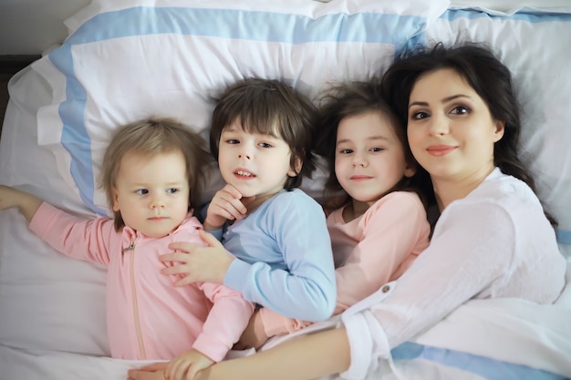 Uma família com crianças se divertindo na cama sob as cobertas durante as férias de natal.