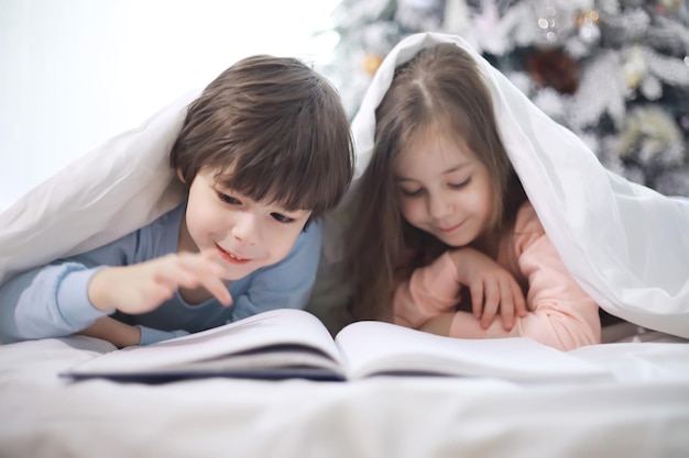 Uma família com crianças se divertindo na cama sob as cobertas durante as férias de Natal