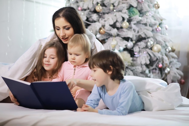 Uma família com crianças se divertindo na cama sob as cobertas durante as férias de Natal