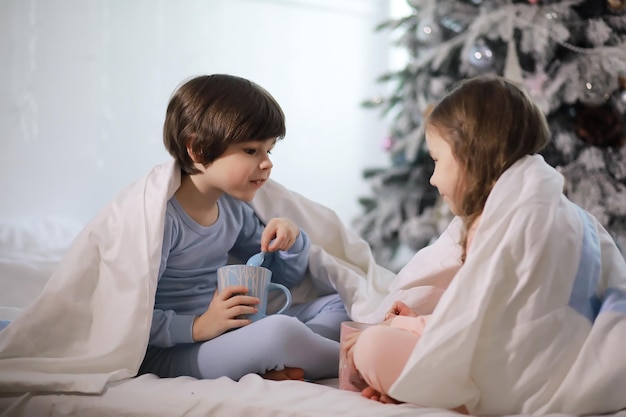 Uma família com crianças se divertindo na cama sob as cobertas durante as férias de Natal