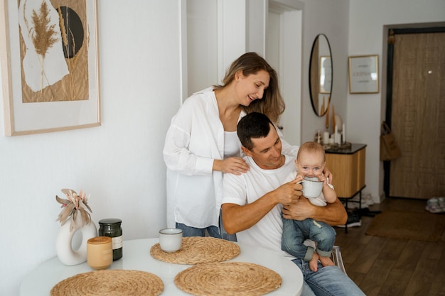 uma família com um bebê está tomando café da manhã na cozinha
