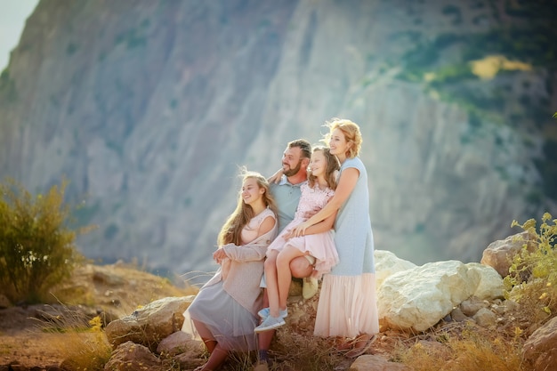 Uma família completa de quatro pais, mãe e duas filhas, todos juntos no topo de uma montanha acima do mar