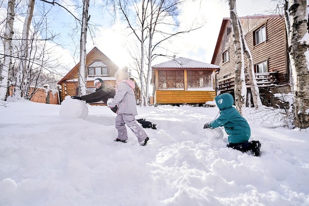 Uma família constrói um boneco de neve no quintal no inverno