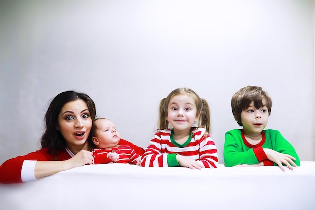 Uma família de pijama listrado está descansando em casa Crianças vestidas de elfos estão deitadas no sofá Família feliz com banner