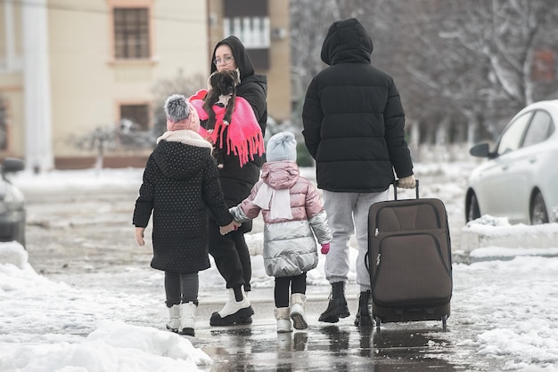 uma família de quatro pessoas deixa a cidade para uma viagem com uma mala grande no inverno