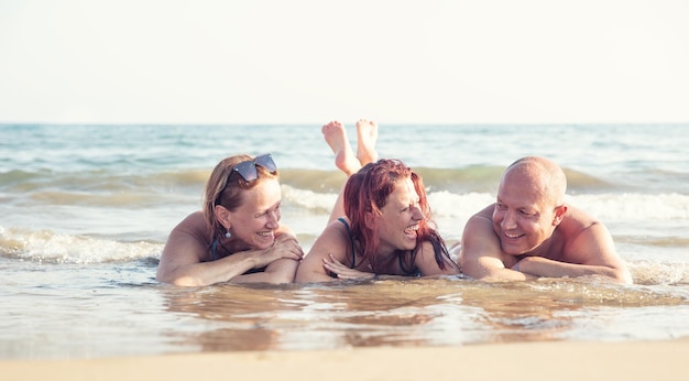 Uma família de três pais, mãe e filha, está deitada à beira-mar e desfrutando de férias conjuntas