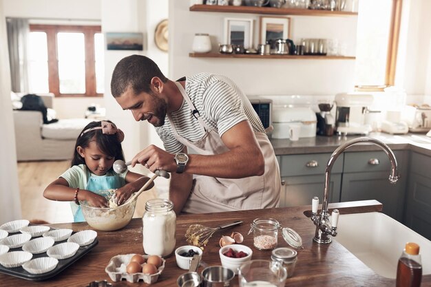 Uma família é uma das naturezas solúveis Tiro de um pai ensinando sua filha a assar na cozinha em casa