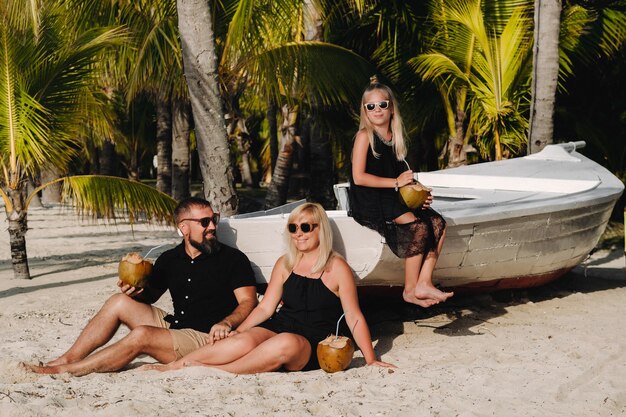 Uma família elegante em roupas pretas com cocos nas mãos na praia da ilha das MauríciasLinda família na ilha das Maurícias, no oceano Índico