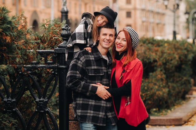 Uma família estilosa de três passeios pela cidade de outono posando para um fotógrafo Pai mãe e filha na cidade de outono