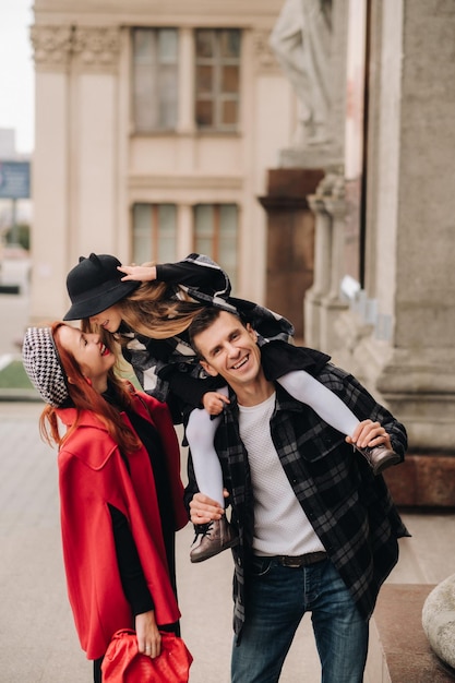 Uma família estilosa de três passeios pela cidade de outono posando para um fotógrafo Pai mãe e filha na cidade de outono