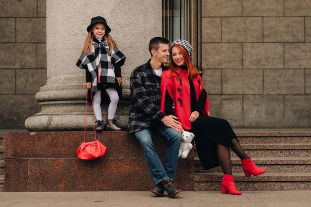 Foto uma família estilosa de três passeios pela cidade de outono posando para um fotógrafo pai mãe e filha na cidade de outono