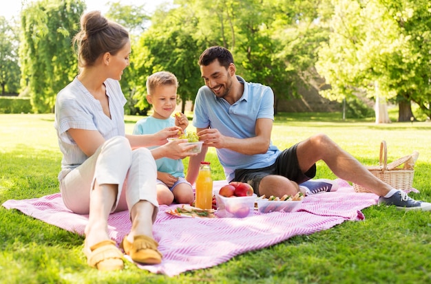 Uma família feliz a fazer um piquenique no parque de verão.