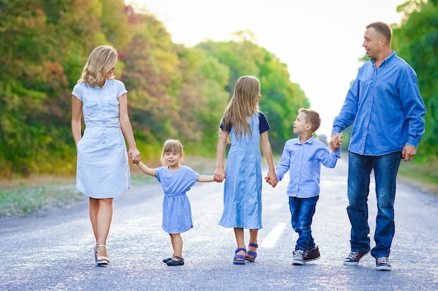 Uma família feliz caminhando pela estrada no parque em uma viagem pela natureza