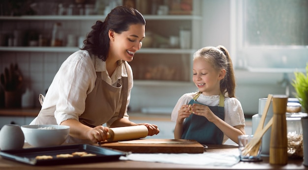 Uma família feliz e amorosa está a preparar a padaria juntos. Mãe e filha estão a cozinhar biscoitos e a divertir-se.