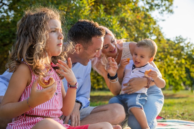 Uma família feliz em um piquenique as crianças fazem um lanche e os pais brincam com eles de perto na família filha no fundo fora de foco