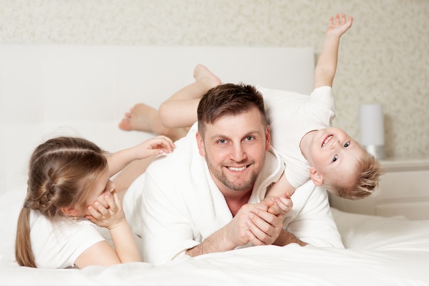 Uma família feliz na cama branca no quarto