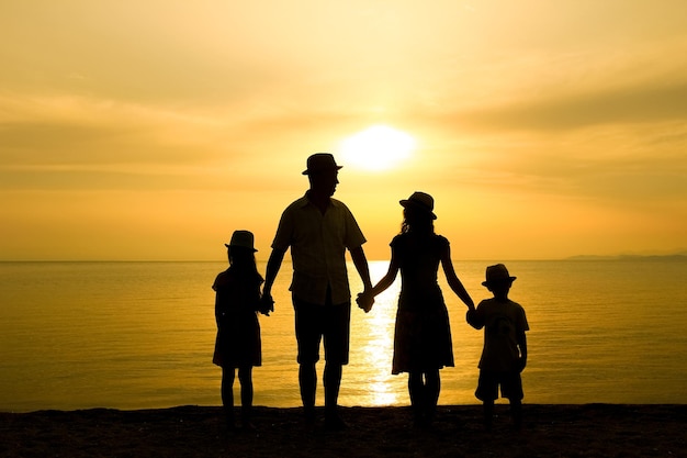 Uma família feliz na natureza à beira-mar em uma silhueta de viagem