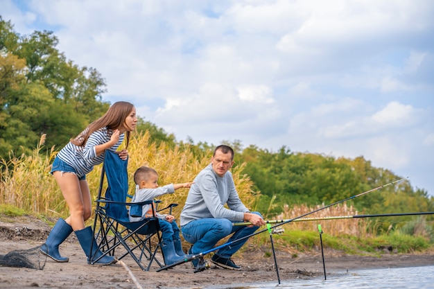 Uma família feliz passa tempo juntos; eles ensinam o filho a pescar.