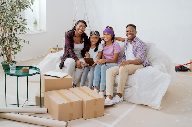 Uma família feliz sentada em um sofá em um apartamento durante uma reforma