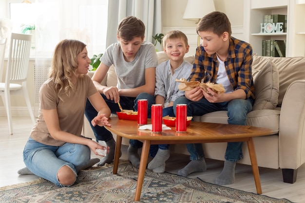 Uma família feliz, uma mulher e três adolescentes comendo fast food em caixas vermelhas e bebendo bebidas em r