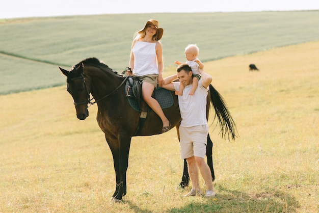 Uma família jovem se diverte no campo. pais e filho com um cavalo