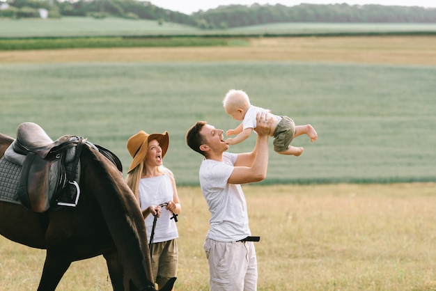 Uma família jovem se diverte no campo. pais e filho com um cavalo