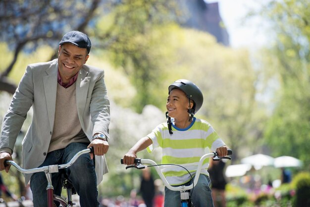 Uma família no parque em um dia ensolarado Andando de bicicleta e se divertindo Um pai e filho lado a lado