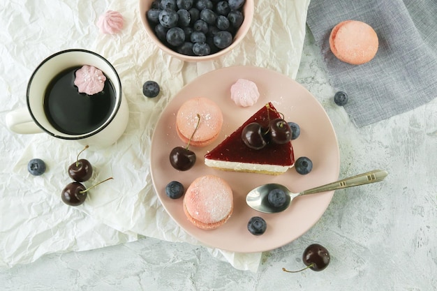 Uma fatia de bolo de frutas com creme em um prato, decorado com frutas, uma xícara de café