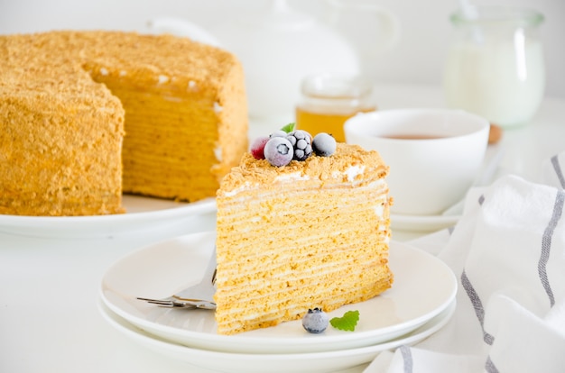 Uma fatia de bolo de mel caseiro com frutas congeladas por cima em um prato branco