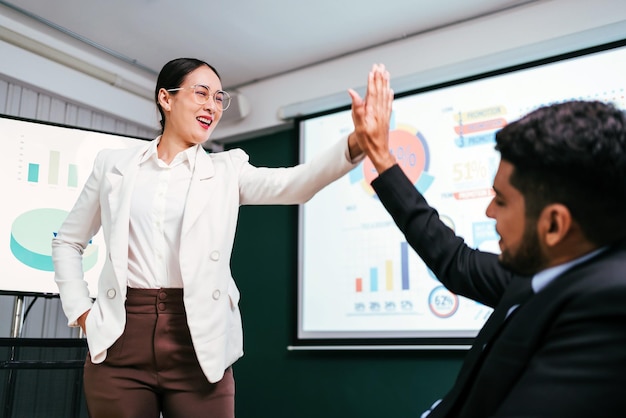 Uma feliz empresária asiática bonita e inteligente comemora fazendo high five e marcando as mãos com seu colega para trabalho em equipe de unidade e projetos de sucesso na sala de reuniões no escritório