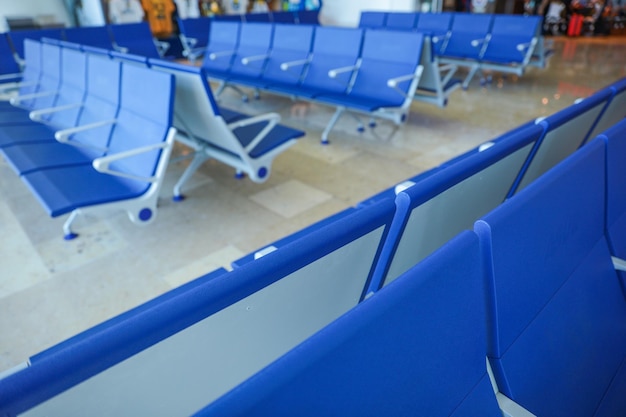 Uma fileira de cadeiras azuis está alinhada em um aeroporto.