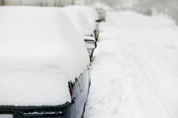 Uma fileira de carros cobertos de neve e uma estrada de inverno Copiar espaço Queda de neve