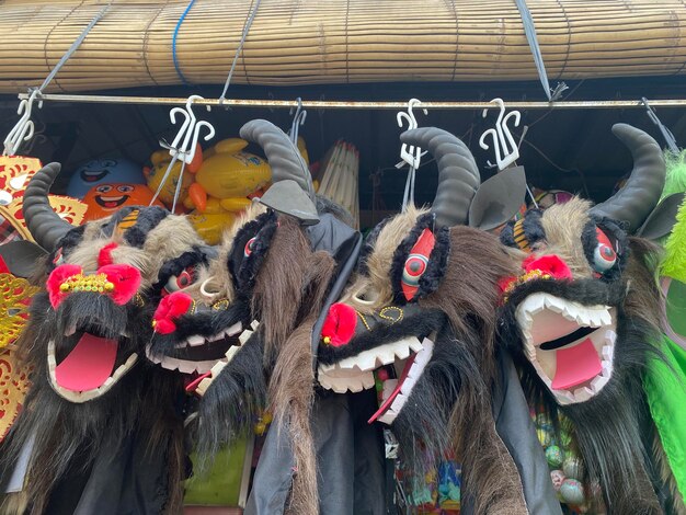 Uma fileira de máscaras de dragão pende de um poste de madeira.