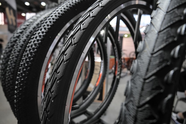 Uma fileira de novos pneus e rodas pretos para uma bicicleta em uma vitrine fechada