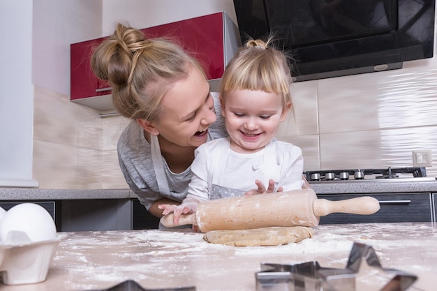 Uma filha pequena passa tempo com a mãe na cozinha para assar biscoitos
