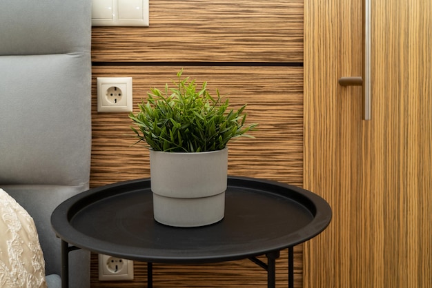 Uma flor verde artificial em um vaso de concreto cinza sobre uma mesa em um quarto moderno