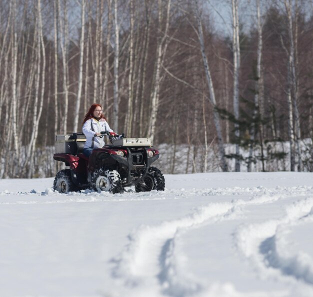 Uma floresta de inverno uma mulher com cabelo ruivo andando de moto de neve grande