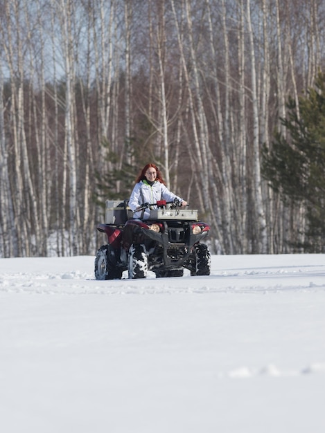 Uma floresta de inverno uma mulher com cabelo ruivo na jaqueta andando de moto de neve