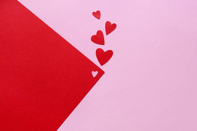 Uma folha de papel rosa com um canto vermelho e pequenas corações vermelhos e lugar para texto