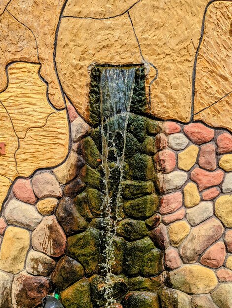 Uma fonte de água com parede de pedra e parede de pedra verde