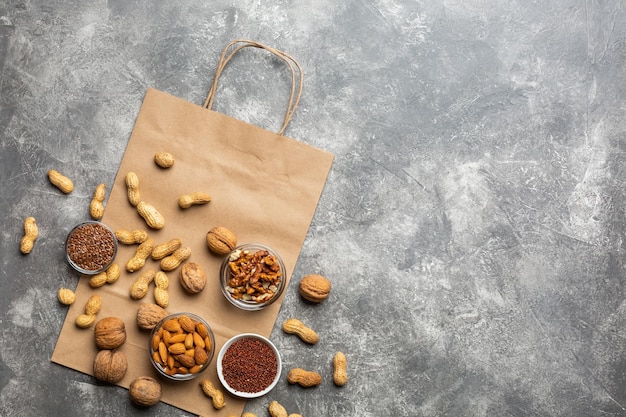 Uma fonte de proteína para vegetarianos: nozes e sementes vista superior em um fundo de concreto com pacote de papel. conceito: compre alimentos saudáveis e limpos.