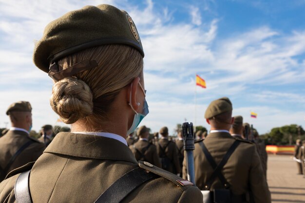 Uma formação de soldados em desfile com uma mulher soldado em primeiro plano