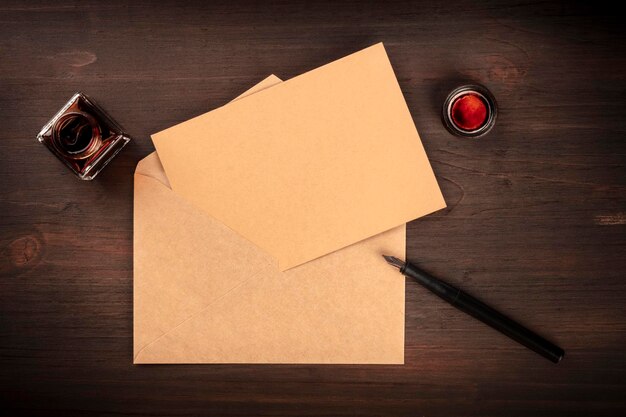 Uma foto aérea de um poço de tinta com um cartão de artesanato marrom em um envelope com uma caneta de tinta e espaço de cópia