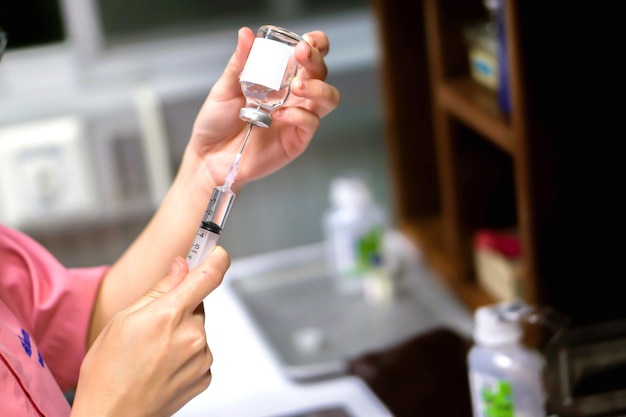 Uma foto das mãos da enfermeira na preparação de uma vacina de injeção para o paciente