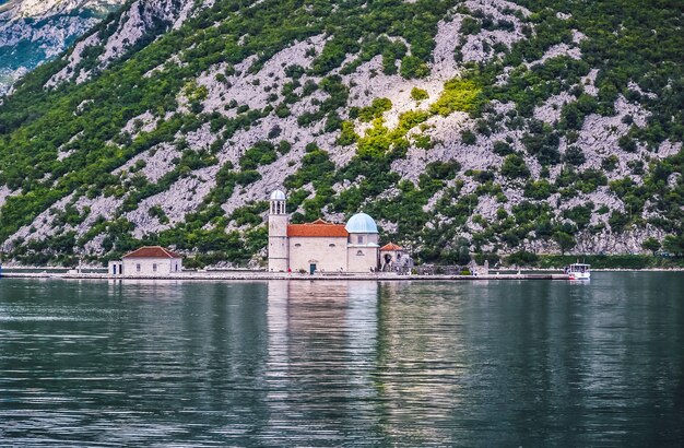 Uma foto de alto ângulo de uma península no mar com uma cordilheira ao fundo da igreja de nossa ...