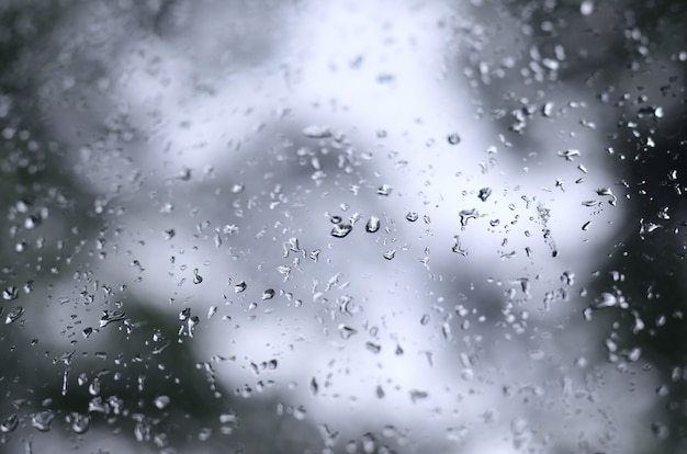 Uma foto de chuva cai no vidro da janela com uma visão turva