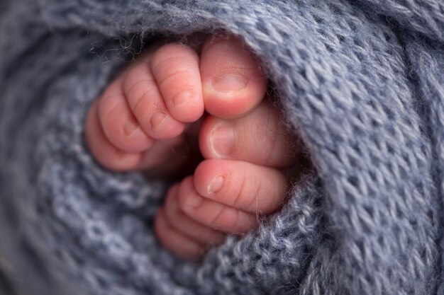 Uma foto de close-up das pernas de um recém-nascido em uma manta cinza claro. pernas e dedos dos pés de um recém-nascido em um cobertor branco macio. foto de alta qualidade