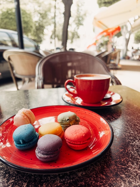 Uma foto de close-up de bolos de macaron macaron coloridos e caneca de café tirada em um café de rua